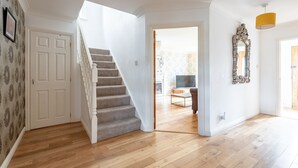 A spacious living area with a wooden floor, a staircase, a large mirror, and a television in the background. - Smugglers' Gait | Anstruther (Anstruther)