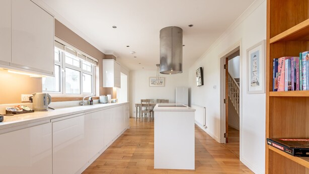 A modern kitchen with white cabinetry, a central island, and a wooden floor. - Smugglers' Gait | Anstruther (Anstruther)