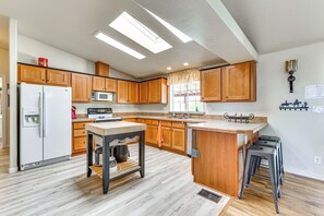 A modern kitchen with wooden cabinets, a central island, a refrigerator, and a microwave. - Furnished Patio! Group Desert Escape in Morristown (Morristown)