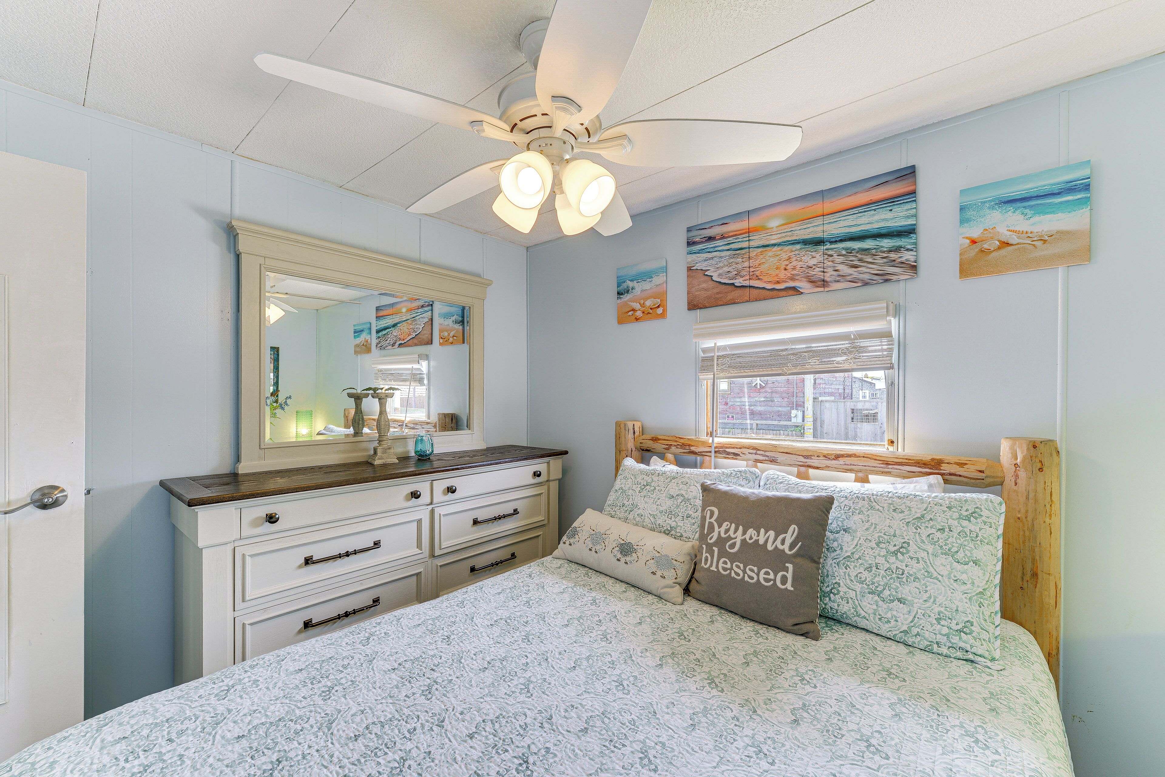 Ein Schlafzimmer mit einem Bett, einer Kommode, einem Deckenventilator und Kunstwerken an den Wänden.
