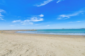 A sandy beach with a rocky breakwater and calm sea. - Peaceful Eureka Beach Cottage w/ 30-foot Dock (Eureka)