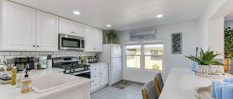 A modern kitchen with white cabinetry, stainless steel appliances, and a large island with seating.