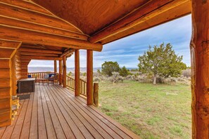 A wooden deck with a view of a grassy field and trees. - Spacious Rifle Cabin w/ Deck + Mountain Views! (Rifle)