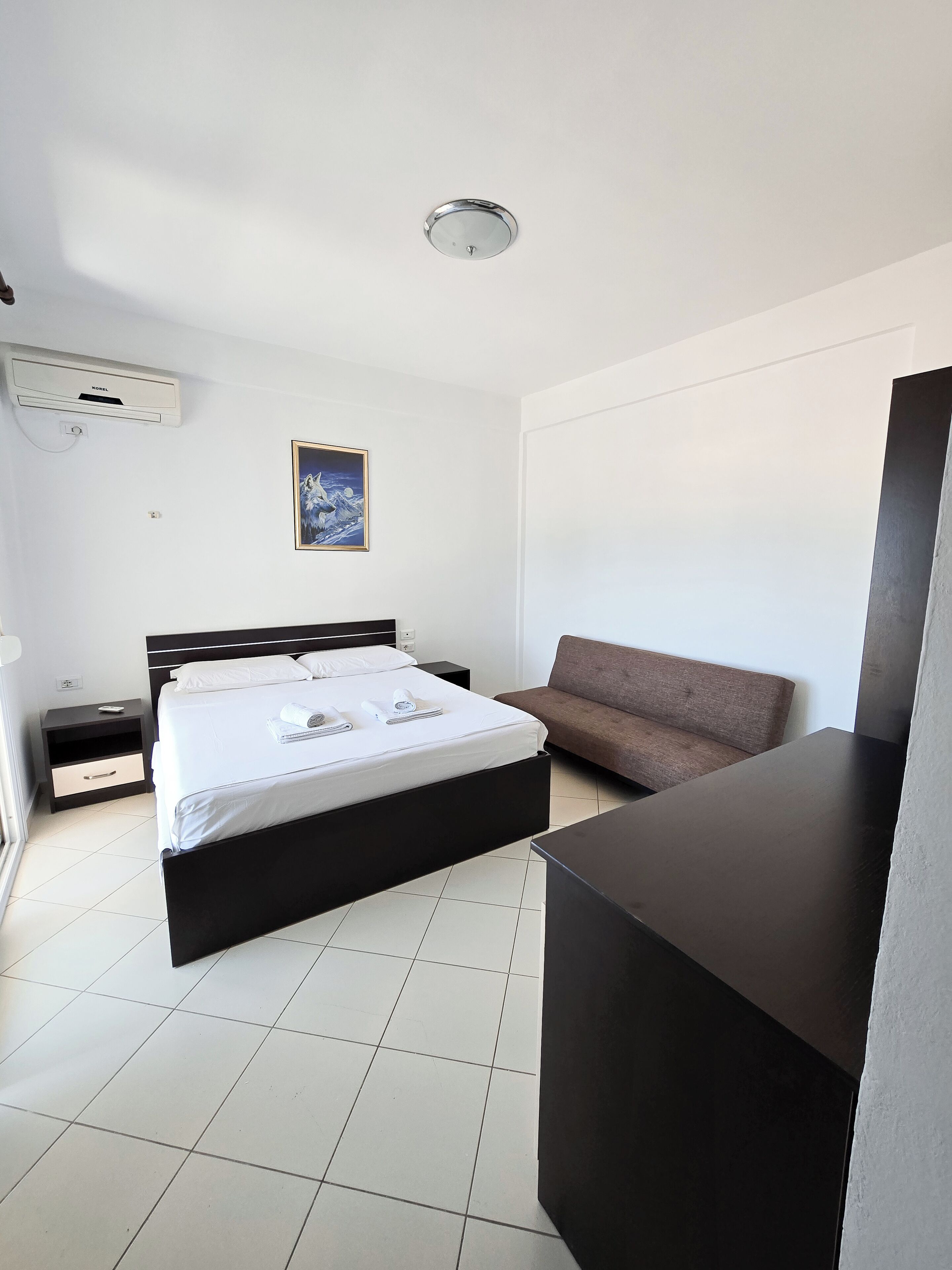 Une chambre d’hôtel moderne, équipée d’un lit, d’un canapé, d’un bureau et d’un tableau au mur.