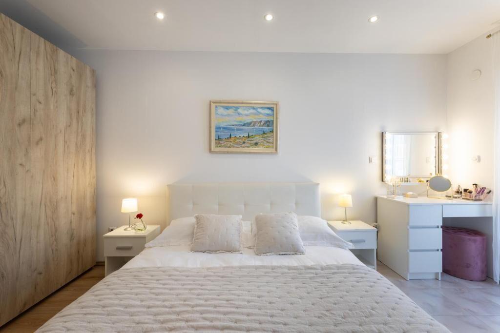 Une chambre à coucher avec un grand lit, une table de chevet avec une lampe, une commode et un tableau au mur.