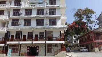 A multi-story building with a traditional architectural style, featuring balconies and a central entrance with a decorative archway.