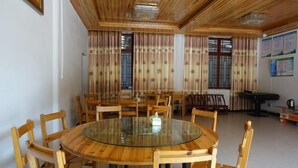 A dining area with round tables and wooden chairs, a ceiling with wooden beams, and a window with curtains. - Guiyuan Villa (Enshi City)