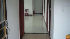 A corridor with a tiled floor, wooden doors, and a small table with a chair. - Guiyuan Villa (Enshi City)
