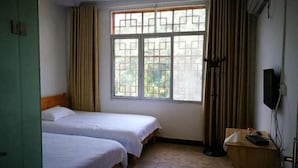 A room with two beds, a window with a view, a desk with a chair, and a television. - Guiyuan Villa (Enshi City)