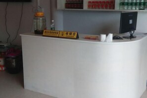 A reception desk with a sign indicating a cashier area, a computer monitor, and a shelf with bottled water. - Guiyuan Villa (Enshi City)