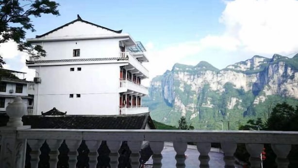 A white building with a traditional roof, a balcony, and a mountainous backdrop. - Guiyuan Villa (Enshi City)