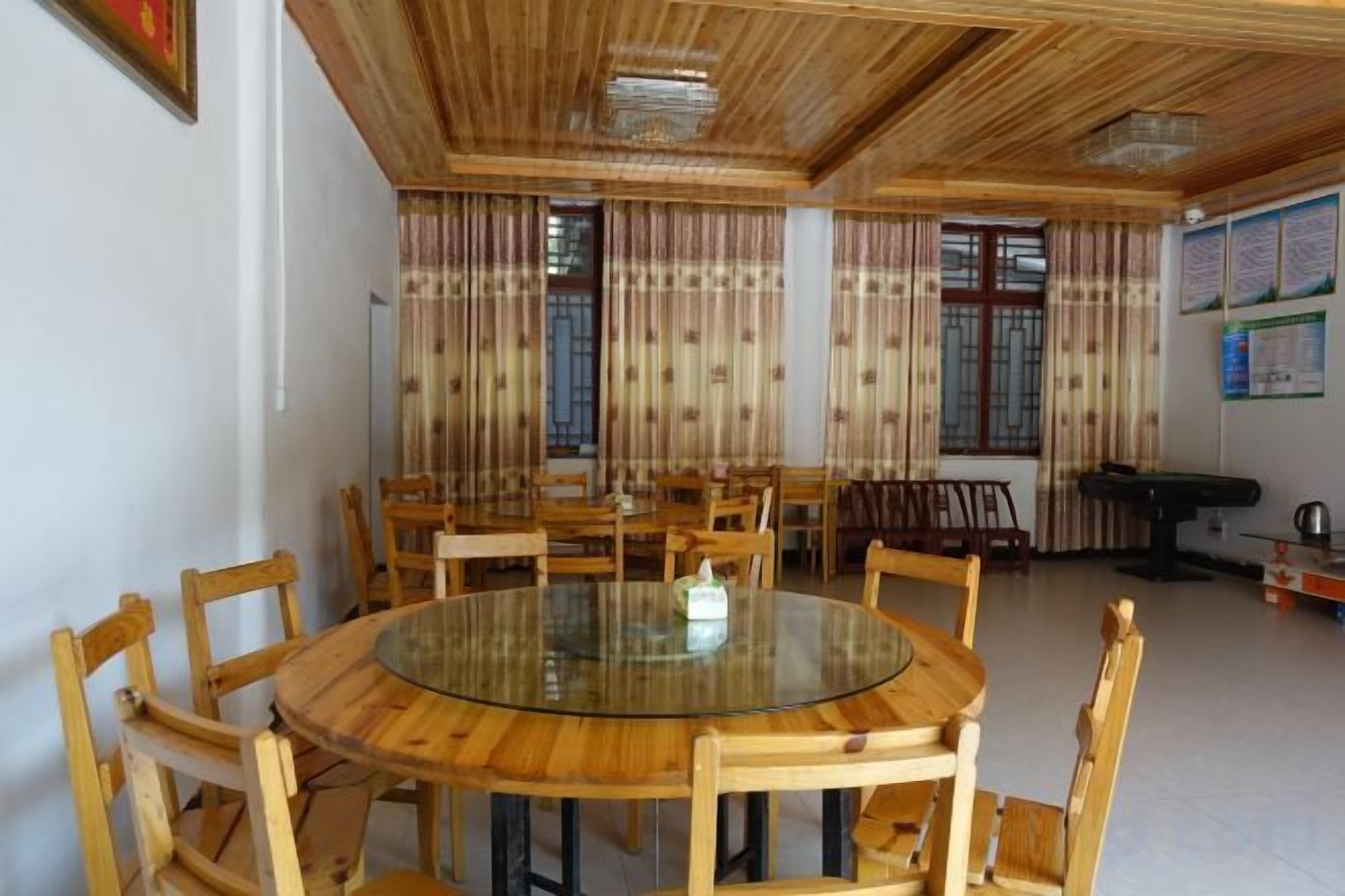 A round table with chairs, a billiards table, and curtains on windows.