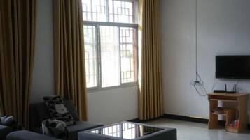 A living room with a sofa, a coffee table, a TV, and curtains.