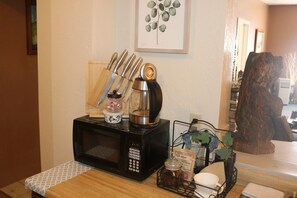 A kitchen counter with a microwave, a coffee maker, and a knife block. There is a framed artwork on the wall and a wooden sculpture in the background. - “Step into Timeless Charm: Discover the Vintage Sanctuary of Toledo, Oregon" (Toledo)
