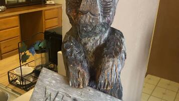 A rustic wooden bear sculpture with a 'WELCOME' sign in front of it.