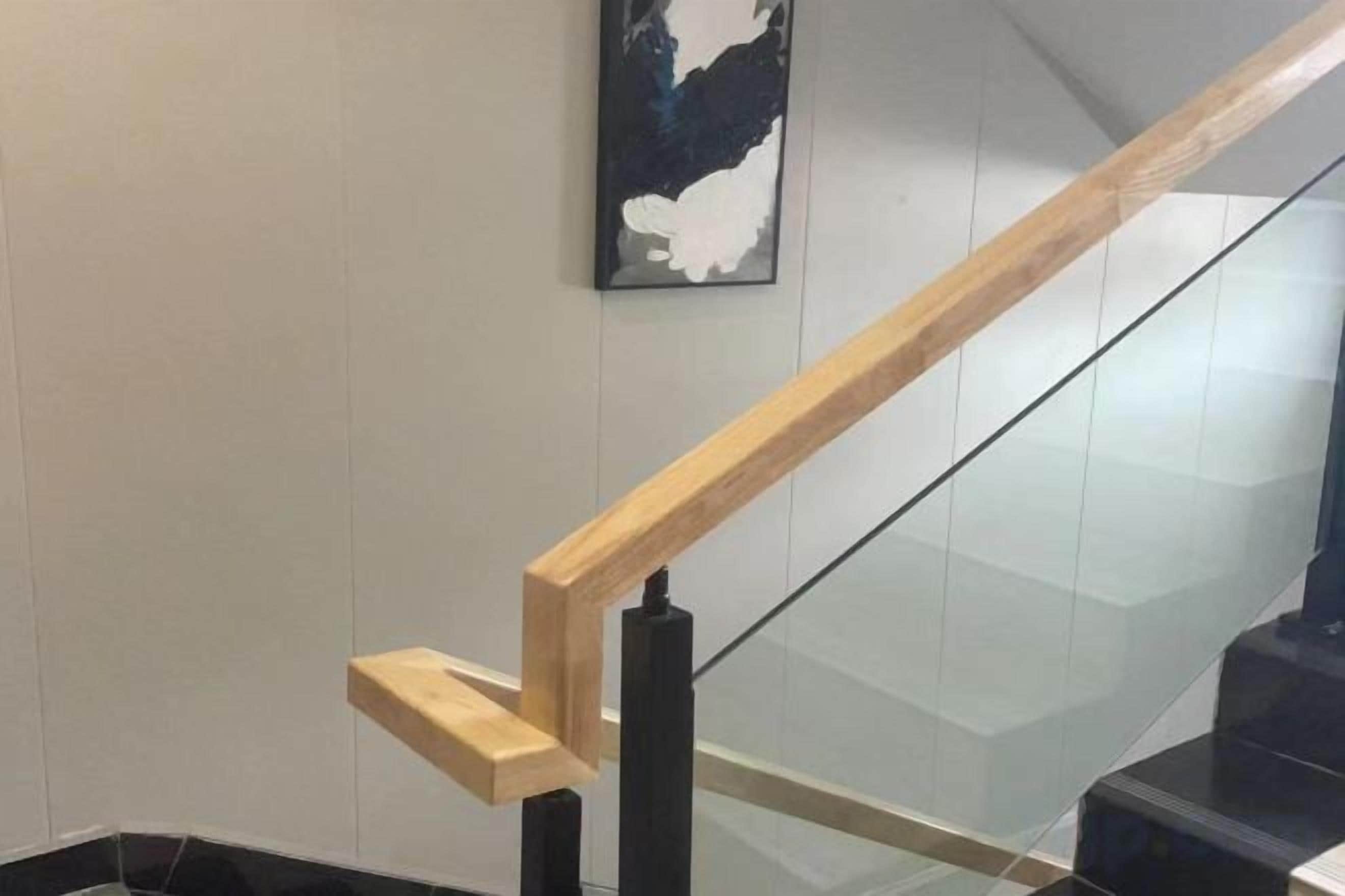 A wooden handrail and glass balustrade of a staircase.