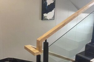 Barandilla de madera y balaustrada de vidrio en una escalera.