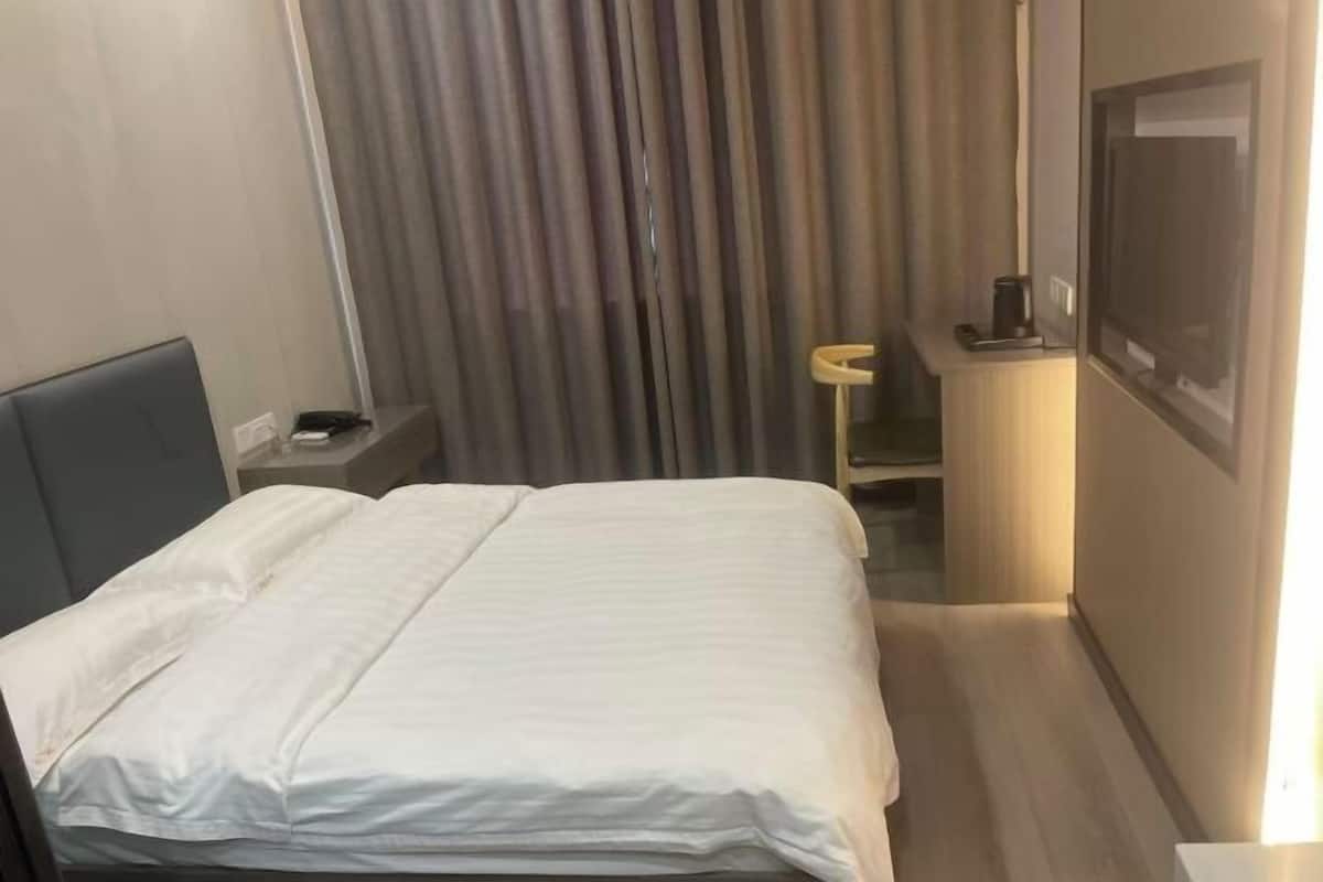 Una habitación de hotel con una cama, una mesita de noche, un televisor y un baño.