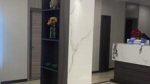 A reception area with a marble column, a reception desk, and a shelf with decorative items. - Huainan Longmen Hotel (Huainan)