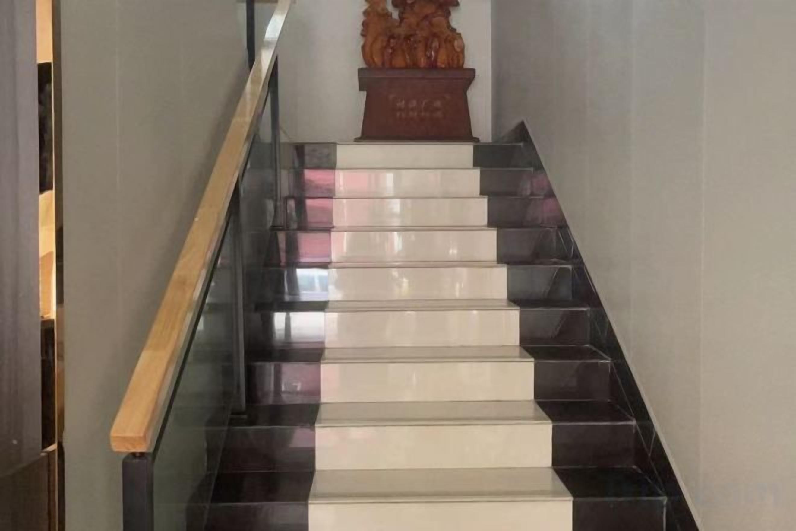 Een trap met afwisselend zwarte en witte treden die uitkomen op een plateau.