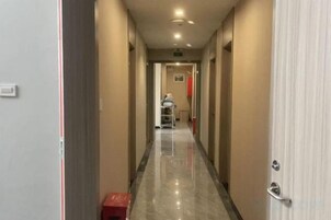 Un pasillo de hotel con piso pulido, puertas a ambos lados y una persona a lo lejos.