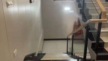 Una escalera con barandilla y protección de vidrio, que conduce a un piso superior.
