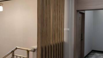 A hallway with a wooden panel wall, a metal railing, and a door leading to another room.
