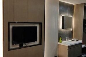 Ein modernes Badezimmer mit einem Wand-Fernseher, einem großen Spiegel und einem Waschtisch.