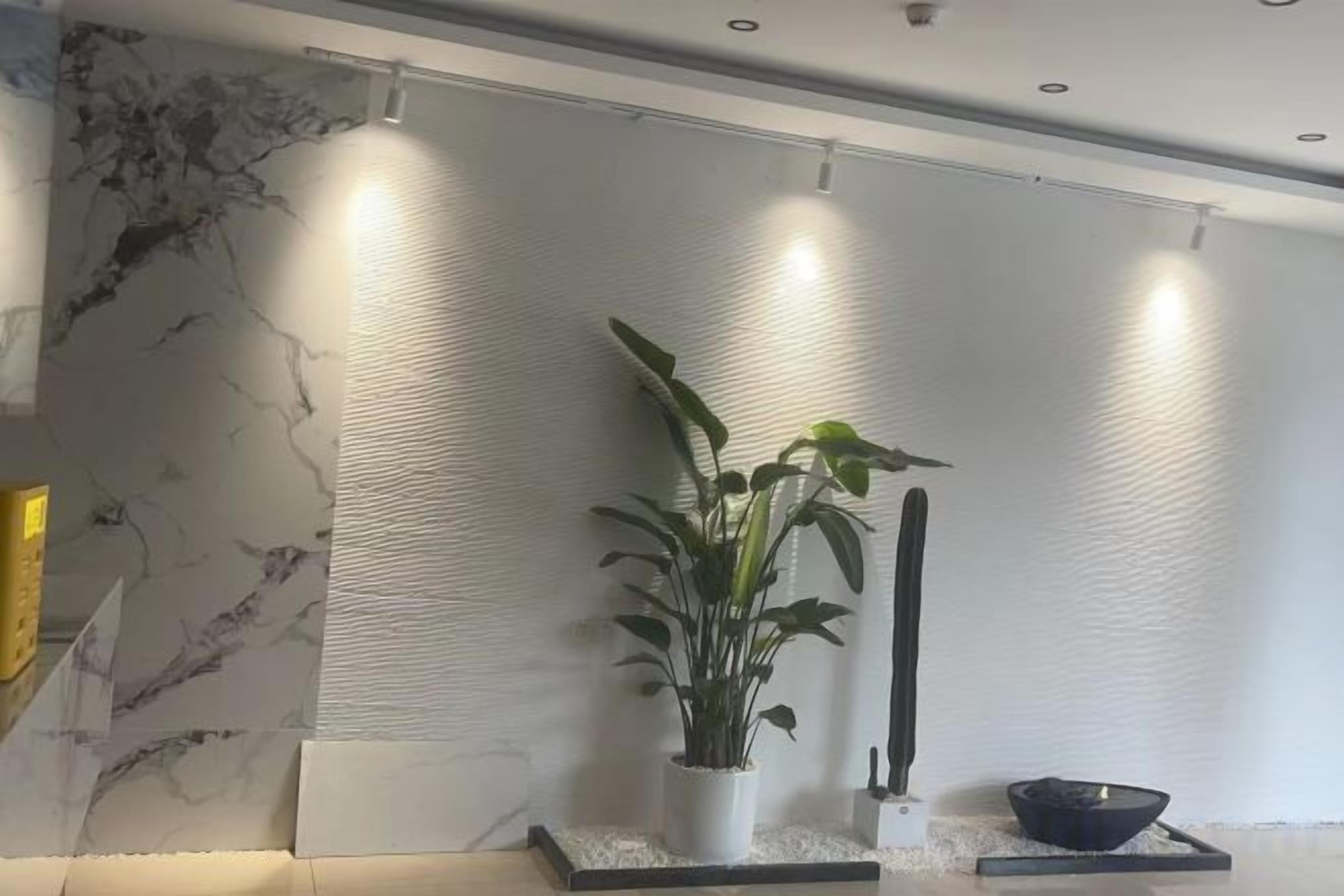 Een modern interieur met een marmeren wand, een potplant en een zwarte kom op een verhoging.