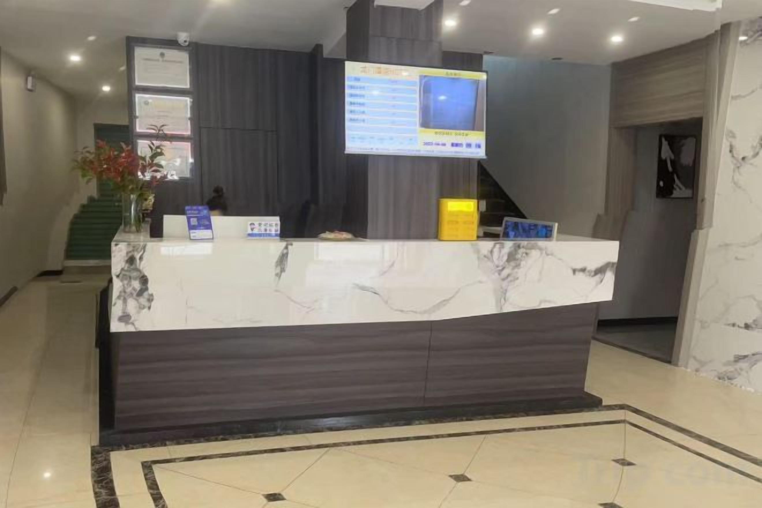 Una recepción con encimera de mármol, un televisor de pantalla plana y una pantalla digital.