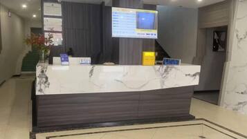 Una recepción con encimera de mármol, un televisor de pantalla plana y una pantalla digital.