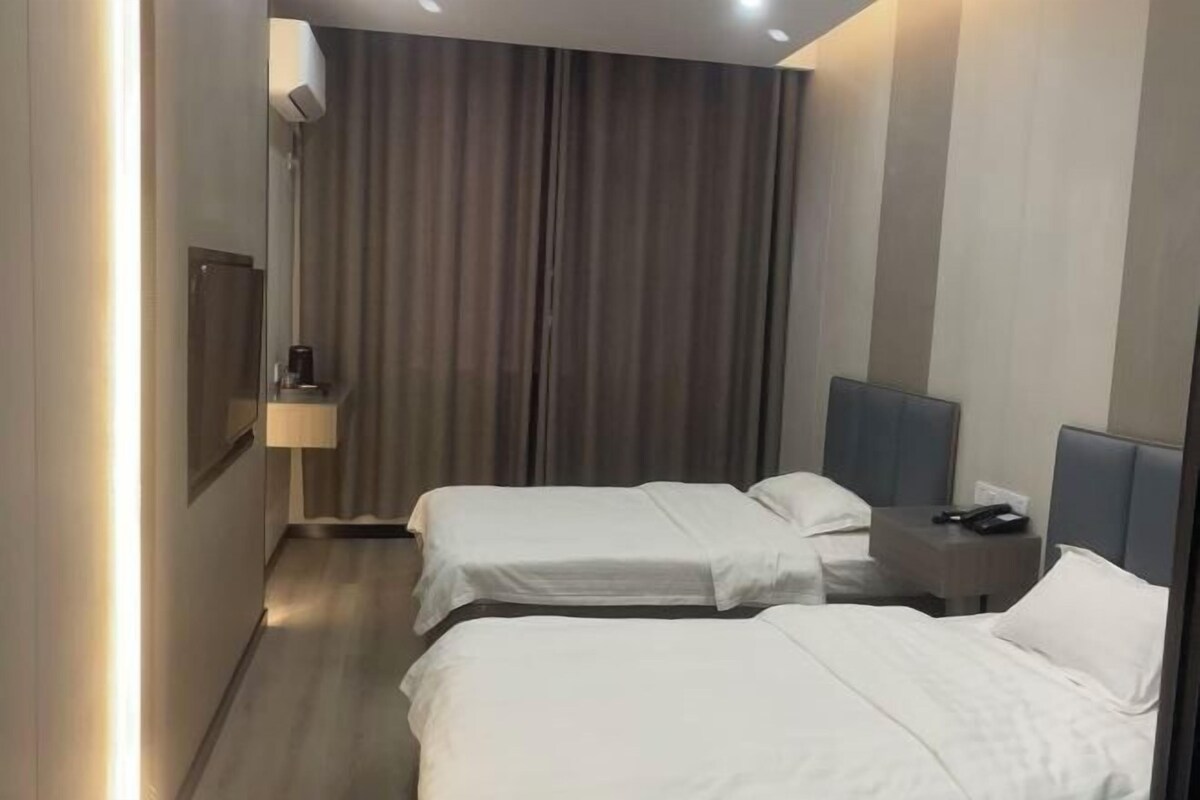 Ein Hotelzimmer mit zwei Betten, einem Nachttisch mit Lampe und einem Vorhang.