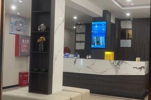A reception area with a marble counter, a digital screen, and a wall-mounted information board. - Huainan Longmen Hotel (Huainan)