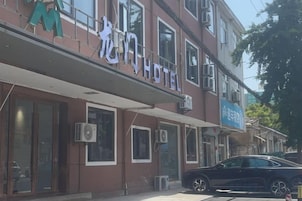 Un hotel con letrero, unidades de aire acondicionado y un automóvil estacionado.