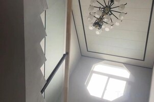 Una escalera con barandilla y un candelabro en el techo.