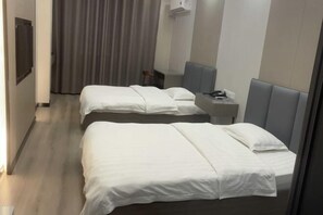 Ein Hotelzimmer mit zwei Betten, einem Schreibtisch, einem Stuhl, einem Fernseher und einem Vorhang.