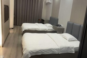 A hotel room with two beds, a desk, a chair, a TV, and a curtain.