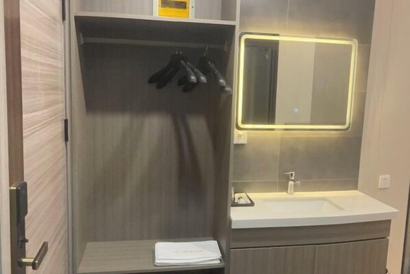 Ein modernes Badezimmer mit einer Duschkabine, einem Waschtisch mit Spiegel und einem Handtuchhalter.