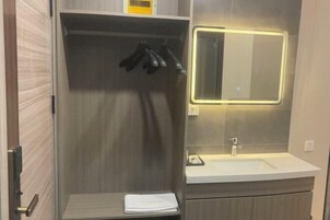 A modern bathroom with a built-in shower, a vanity with a mirror, and a towel rack.