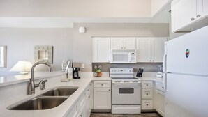 Een moderne keuken met witte kasten, roestvrijstalen apparatuur en een dubbele spoelbak.