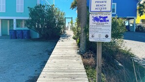 A wooden boardwalk leading to a private beach area with a sign indicating 'Lagoon Tower Private Beach Access' and a turtle protection notice. - Steps to the beach and Dock on the Bay! Pool, family and pet friendly! (Gulf Shores)