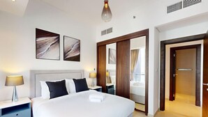 Une chambre d’hôtel moderne avec un grand lit, des tables de chevet, une armoire et des œuvres d’art accrochées au mur.