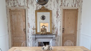 Ein Esszimmer mit Holztisch, klaren Stühlen, einem Ziertegelspiegel und einem Kamin.