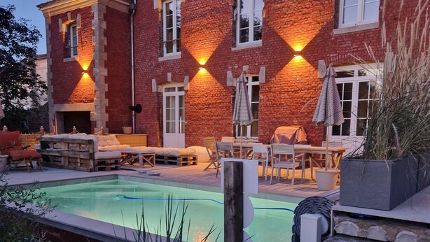 Ein Gebäude aus Backstein mit Pool, Außenbereich und einer gut beleuchteten Fassade.