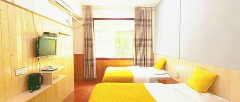 A hotel room with two beds, a television, and a window with curtains.