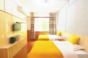 Habitación de hotel con dos camas, un televisor y una ventana con cortinas.