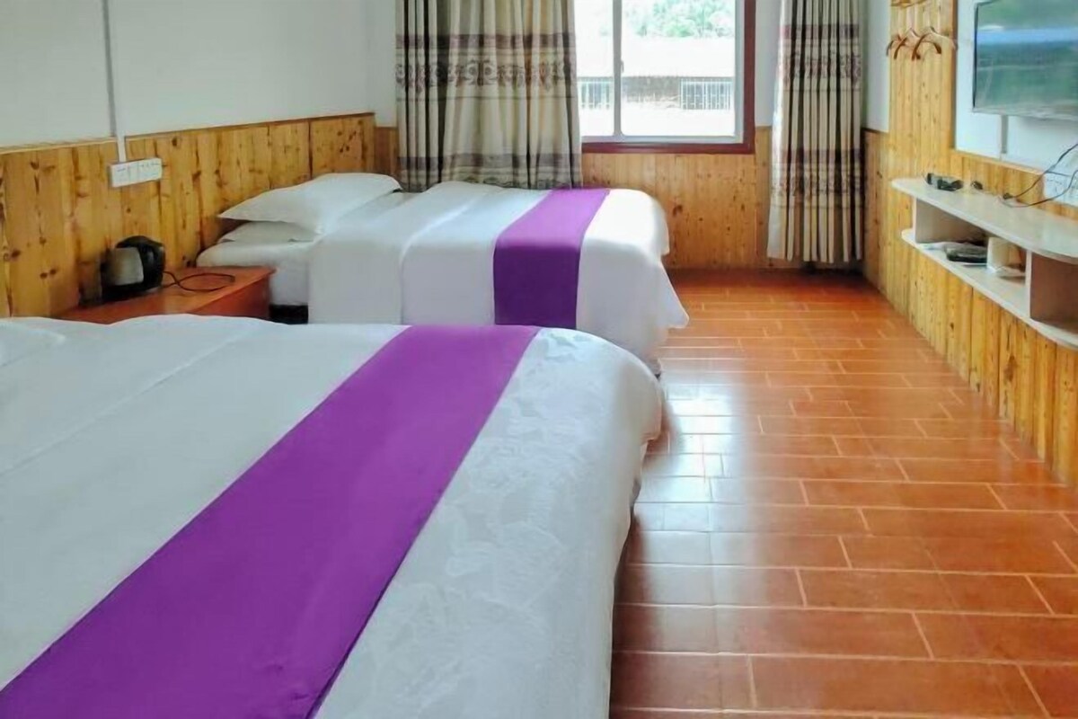 Une chambre d’hôtel avec deux lits, une télévision, un mur en bois et une fenêtre avec des rideaux.