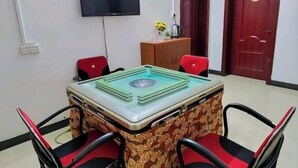 Ein Konferenzraum mit einem Tisch mit Glasplatte, roten Stühlen, einem an der Wand montierten Fernseher und einer Holzkassette mit Blumen.