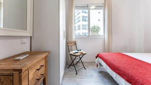 A bedroom with a wooden dresser, a chair, a bed with a red blanket, and a window with curtains. - Faro's Angel Miraflores Penthouse (Mijas)