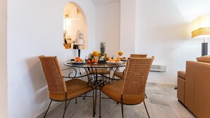 A dining area with a round table, four wicker chairs, and a sofa. - Faro's Angel Miraflores Penthouse (Mijas)